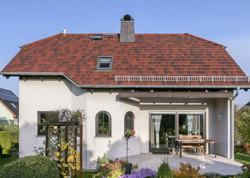 Cottage Flachziegel auf Walmdach eines Einfamilienhauses in der Gesamtansicht mit Terrasse