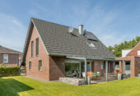 Schräge Gesamtansicht von Klinkerhaus mit Satteldach und Flachziegel in edelschiefer
