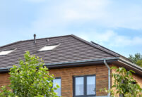 Einfamilienhaus mit zwei Vollgeschoßen, Holzverkleidung und auf dem Dach unser Walther Stylist in anthrazit mit Foto vom Grad und Firstziegel
