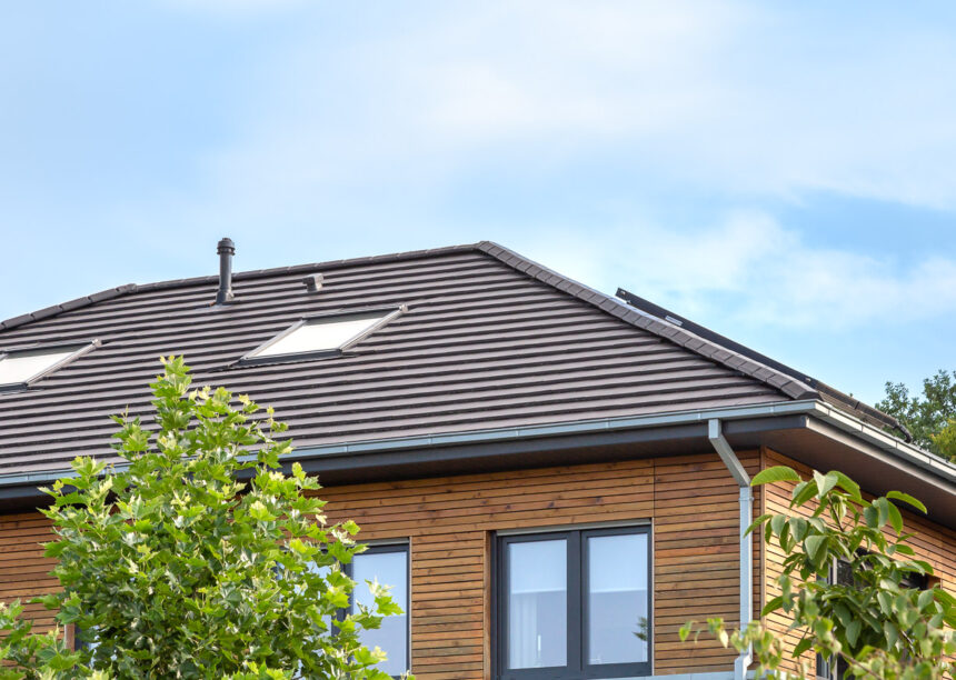 Einfamilienhaus mit zwei Vollgeschoßen, Holzverkleidung und auf dem Dach unser Walther Stylist in anthrazit mit Foto vom Grad und Firstziegel