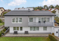 Frontale Ansicht von saniertem Einfamilienhaus mit modernem dunklen Dach, hier in edelnero