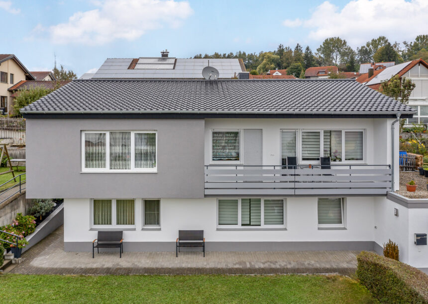 Frontale Ansicht von saniertem Einfamilienhaus mit modernem dunklen Dach, hier in edelnero