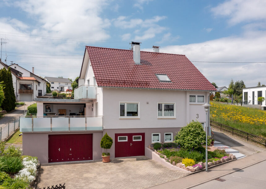Einfamilienhaus mit Flachdachziegel W6v auf diesem Foto in der Gesamtansicht mit Garage und Dachterrasse.