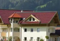 Ein Hotel gedeckt mit den Dachziegelmodell W6v in edelrosso, das Satteldach hat ein Turmdach und mehrere Gauben