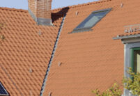 Flachdachziegel W4v in rotbraun auf öffentlichem Gebäude mit Fokus auf die Dachkehle