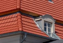 Tradition in rotbraun auf Mehrfamileinhaus mitten in der Stadt - der Dachziegel von Jacobi im Doppelmuldendesign. Im Bildfokus der formschöne Gradanfänger in Muschelform aus dem keramischen Jacobi-Zubehör