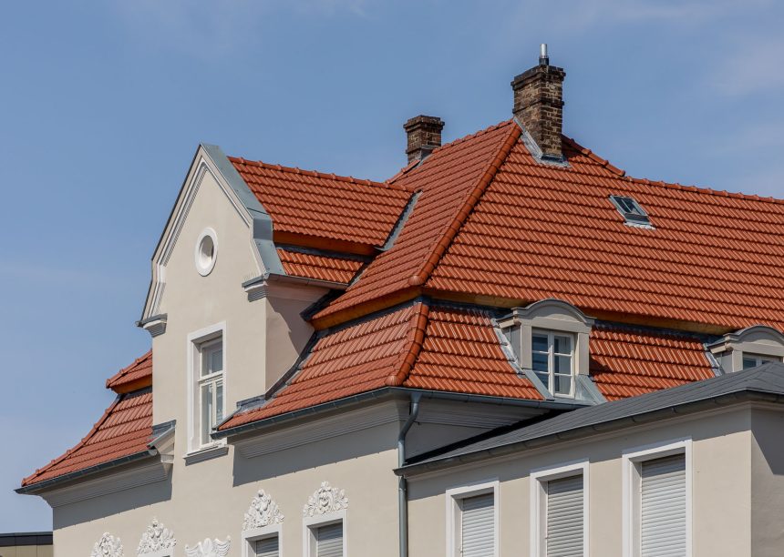 Tradition in rotbraun auf Mehrfamileinhaus mitten in der Stadt - der Dachziegel von Jacobi im Doppelmuldendesign. Im Bildfokus der das Walmdach mit Fußwalm