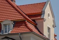 Tradition in rotbraun auf Mehrfamileinhaus mitten in der Stadt - der Dachziegel von Jacobi im Doppelmuldendesign. Im Bildfokus der Walm mit Fußwalm und der schöne Erker