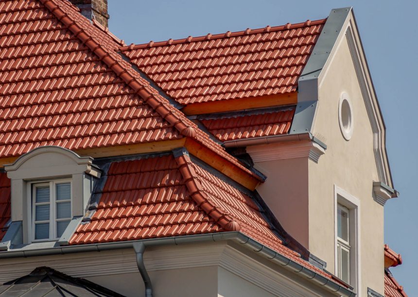 Tradition in rotbraun auf Mehrfamileinhaus mitten in der Stadt - der Dachziegel von Jacobi im Doppelmuldendesign. Im Bildfokus der Walm mit Fußwalm und der schöne Erker