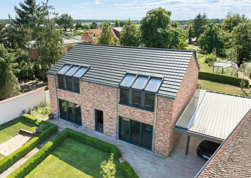 Dachziegel Stylist in edelschiefer auf modernem Klinkerhaus, hier in der Gesamtansicht mit Garteneinblick