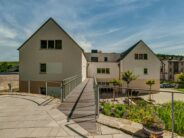 U-förmiges Wohnhaus mit Großflächenziegel Z10 in altschwarz auf den Satteldächern mit Holzsteg und schönem Innenhof