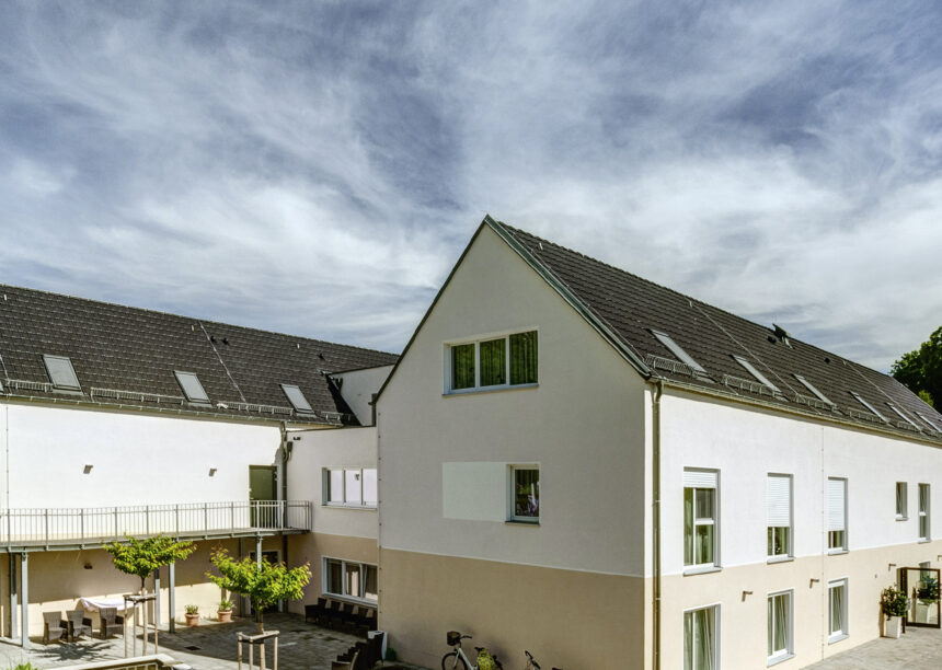 U-förmiges Wohnhaus mit Großflächenziegel Z10 in altschwarz auf den Satteldächern seitlich fotografiert mit schönem Innenhof