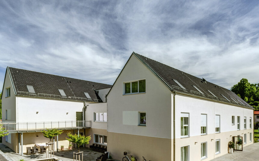 U-förmiges Wohnhaus mit Großflächenziegel Z10 in altschwarz auf den Satteldächern seitlich fotografiert mit schönem Innenhof
