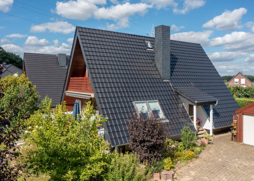 Dachhaus mit edelschwarzen Reformziegeln Z10. Hier der Eingangsbereich und überdachter Holzbalkon am Giebel.