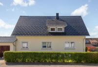 Glanzvolles Dach mit Reformziegel Z10 in edelspacgrau mit Schneestopnasen mit Hecke auf dem Foto