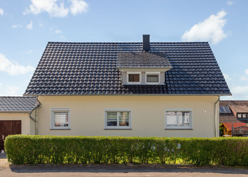 Glanzvolles Dach mit Reformziegel Z10 in edelspacgrau mit Schneestopnasen mit Hecke auf dem Foto