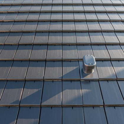 Dachziegel Stylist in edelschiefer mit Fokus auf den Sanilüfter. Der Flachziegel ist in Reihe verlegt