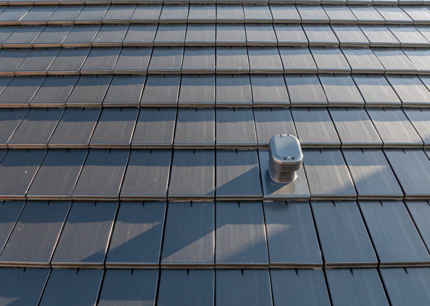 Dachziegel Stylist in edelschiefer mit Fokus auf den Sanilüfter. Der Flachziegel ist in Reihe verlegt