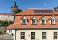 viele Satteldachgauben auf Mansarddach mit Dachziegel K1 - linksdecker mit Kirche im Hintergrund