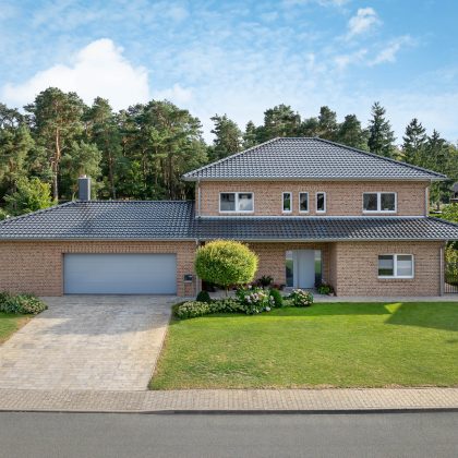 J11v in spacegrau auf Walmdach mit Fußwalm - mit Klinkerfassade und schöner Grünanlage