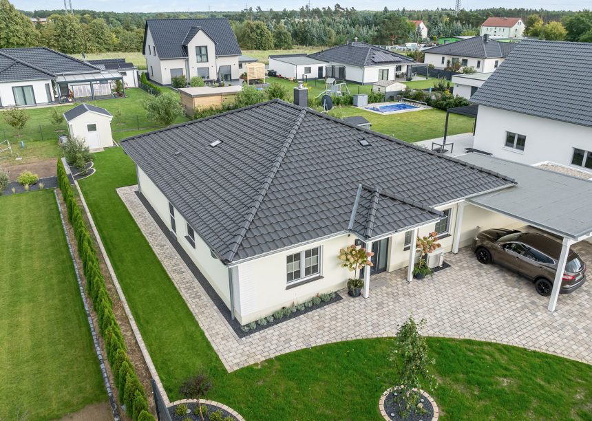 Gesamtansicht von Bungalow mit Carport und Hofeinfahrt sowie Walmdach mit Walmkappen und Dachziegel J11v und Firstziegel F6v