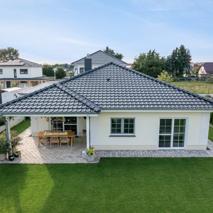 Gesamtansicht von Bungalow mit Terrasseneinblick und Walmdach mit Walmkappen und Dachziegel J11v und Firstziegel F6v