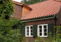 Z5 in altrot auf schön saniertem Klinker-Wohnhaus mit Fokus auf die Kehle und Holzverkleidung an der Satteldachgaube