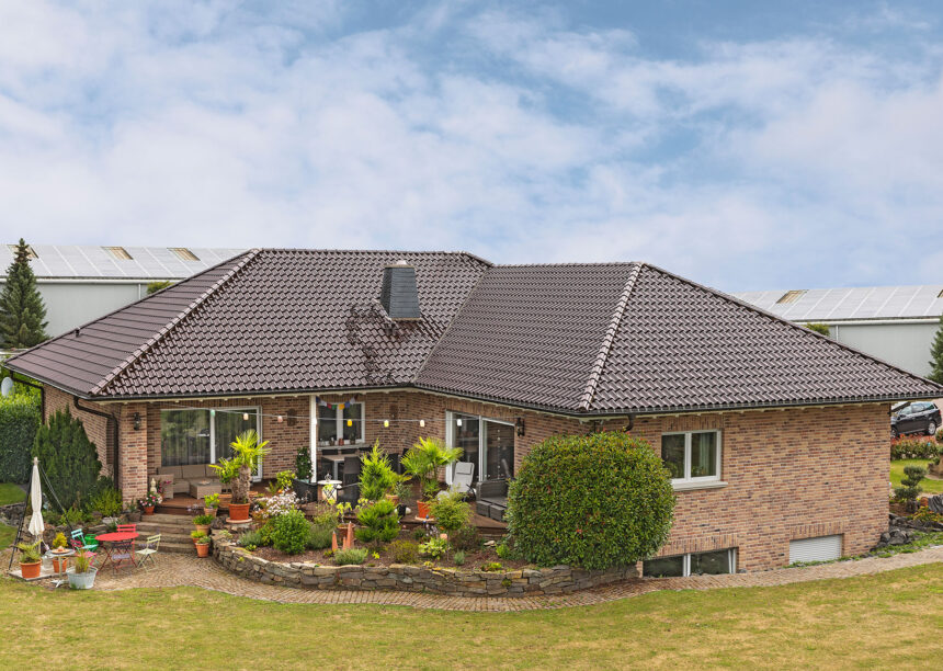 Stilvoller Bungalow mit maronenbraunen Dachziegel auf dem Walmdach mit Fokus auf die Terrasse