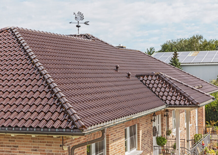 Stilvoller Bungalow mit maronenbraunen Dachziegel auf dem Walmdach in der schrägen Dachansicht