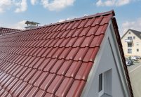 W6v in edelrosso auf L-förmigen Satteldach, der beliebte Dachziegel für Süddeutschland und Österreich - im Fokus die Ortgänge und Anfangsscheibe für den First