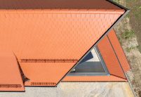 Biberdach in rotbraun mit Schneefanggitter auf besonderer Dachform aus der Vogelperspektive