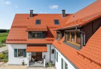 Biberdach in rotbraun mit Schneefanggitter auf besonderer Dachform