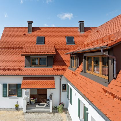 Biberdach in rotbraun mit Schneefanggitter auf besonderer Dachform
