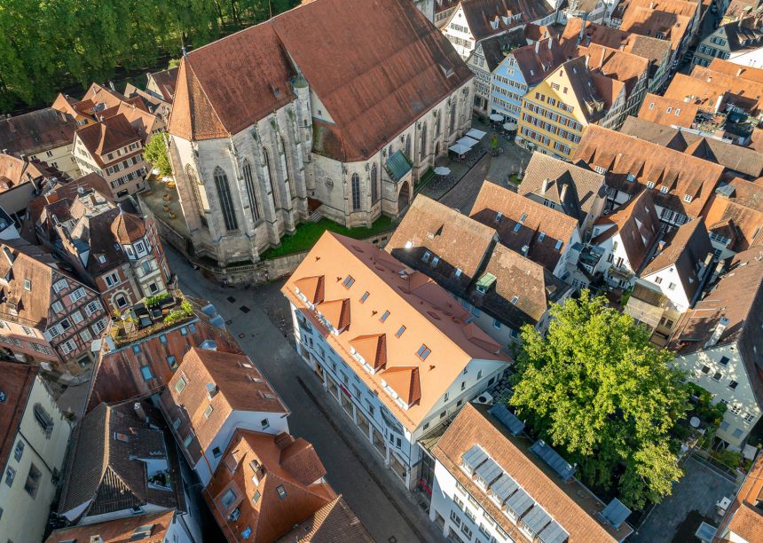 Dach mitten in der Stadt mit Jacobi Biber Rundschnitt in naturrot schräg mit Kirche aus der Vogelperspektive