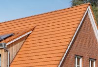 Giebel mit Firstanfänger und Ortgängen re/li im Bildfokus und Dachziegel Doppelmulde Z2 in naturrot auf Jugrendtreff verklinkerten Fassade