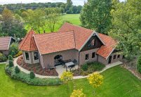 Traumhaftes Klinker-Holz-Haus mit Turm und Hohlfalzziegel Z5 in friesisch-bunt Salzbrand von Jacobi Dachziegel aus der schrägen Drohnenansicht