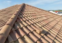 Romanische Pfanne, der mediterrane Dachziegel von Jacobi, in der Sonderserie Bella Casa auf gesamten Anwesen: Haus mit Walmdach und Nebengebäude hier eine Detailansicht von First und Sanitärlüfter aus dem nichtkeramischen Zubehör