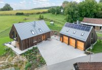 Dachziegel Stylist in edelgrau auf Holzvertäfelten Einfamilienhaus mit hochwertigem Jacobi Zubehör, Schneefanggitter, Sanitärlüfter und PV Solarträger mit Garage und PV-Anlage
