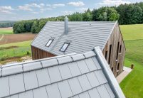 Dachziegel Stylist in edelgrau auf Holzvertäfelten Einfamilienhaus mit hochwertigem Jacobi Zubehör, Schneefanggitter, Sanitärlüfter und PV Solarträger universal fotografiert mit First im Vordergrund