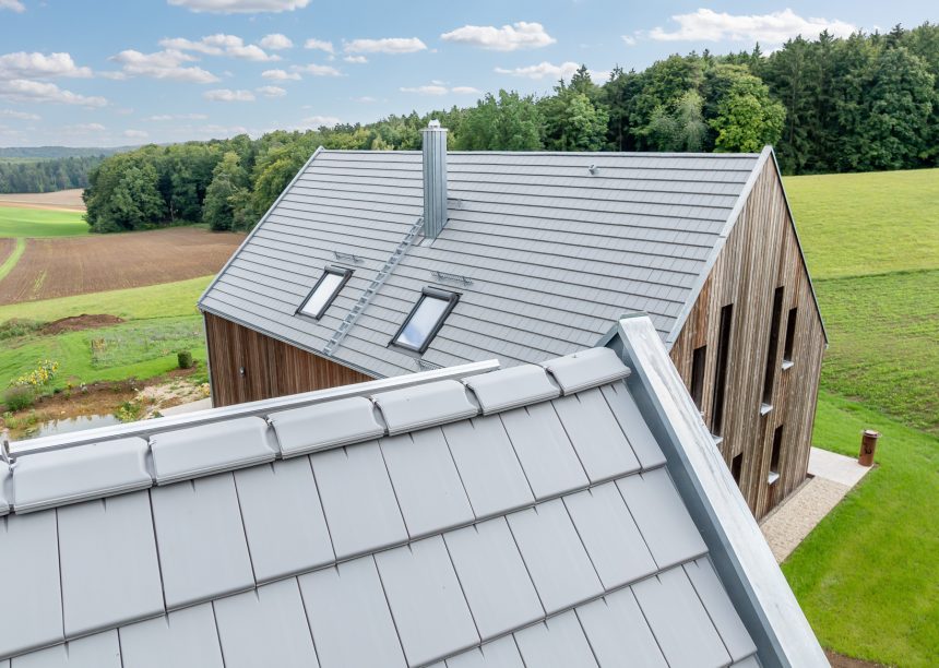 Dachziegel Stylist in edelgrau auf Holzvertäfelten Einfamilienhaus mit hochwertigem Jacobi Zubehör, Schneefanggitter, Sanitärlüfter und PV Solarträger universal fotografiert mit First im Vordergrund