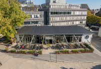 Öffentliches Gebäude mit PV Lösung von Jacobi: Solarziegel Stylist PF mit Flachziegel Stylist in samtschwarz aus der schrägen Luftansicht