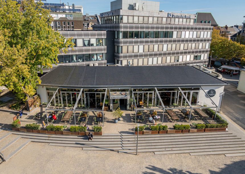 Öffentliches Gebäude mit PV Lösung von Jacobi: Solarziegel Stylist PF mit Flachziegel Stylist in samtschwarz aus der schrägen Luftansicht