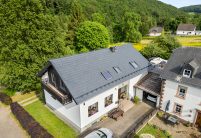 Drohnenaufnahme von Referenzobjekt mit J11v in der Glasur lavagrau matt auf einem sehr hochwertig saniertem Einfamilienhaus mit Jacobi Dachziegel Zubehör