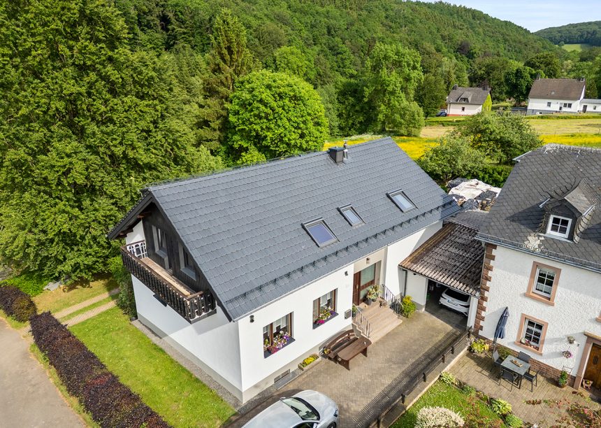 Drohnenaufnahme von Referenzobjekt mit J11v in der Glasur lavagrau matt auf einem sehr hochwertig saniertem Einfamilienhaus mit Jacobi Dachziegel Zubehör