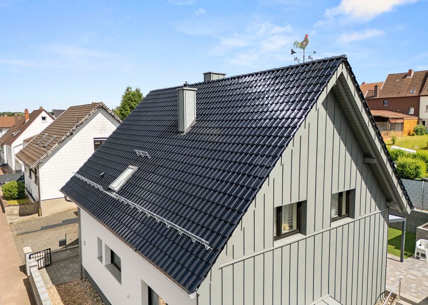 Einfamilienhaus mit blauem Dach: Neubau mit Dachziegel J13v in marineblau aus mit Giebeldetails und formschönen Firstanfänger im Bild