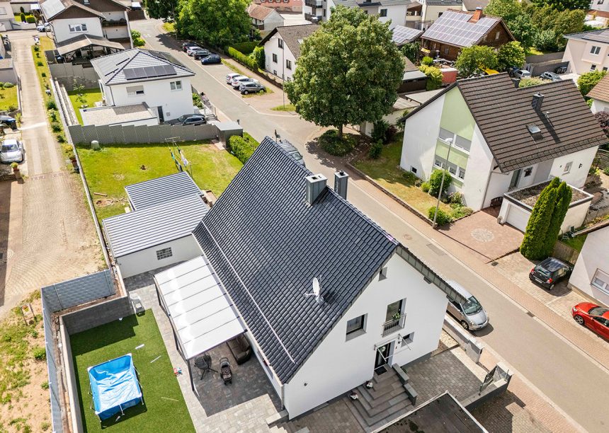Einfamilienhaus mit blauem Dach: Neubau mit Dachziegel J13v in marineblau aus der schrägen Luftansicht
