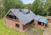 Klinkerhaus mit Dachziegel Z5 in edelschwarz auf Satteldach mit besonderer Fledermausgaube in der schrägen Gesamtansicht mit Garten und Terrasse