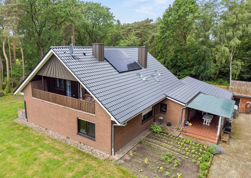 Klinkerhaus mit Dachziegel Z5 in edelschwarz auf Satteldach mit besonderer Fledermausgaube in der schrägen Gesamtansicht mit Garten und Terrasse
