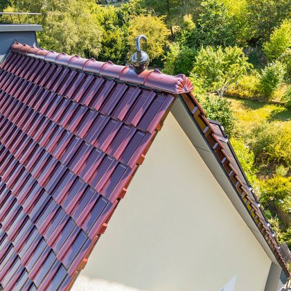 Giebel von Sanierungsobjekt mit extremen Steildach in der besonderen Oberfläche bordeauxrot