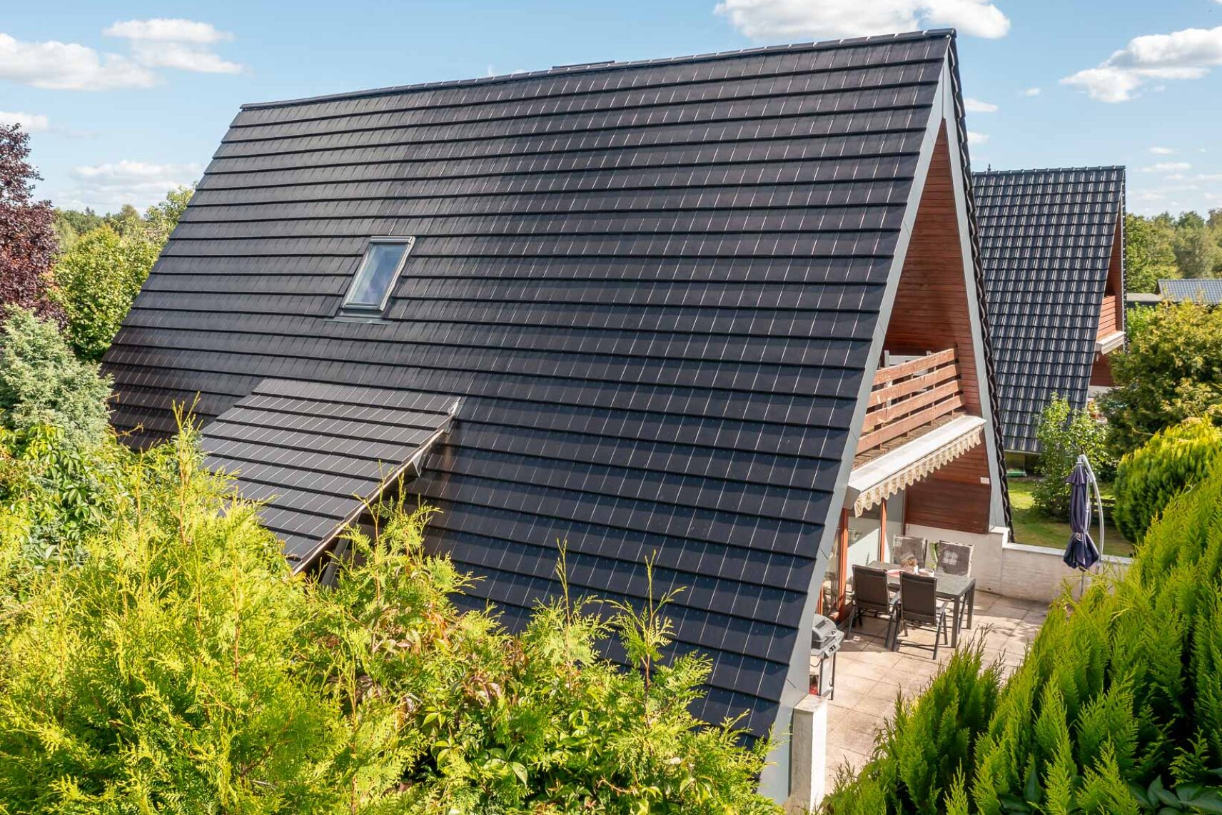Ein Nurdachhaus aus Flachziegeln WALTHER Stylist® mit Blick auf die Terrasse und Vordach.